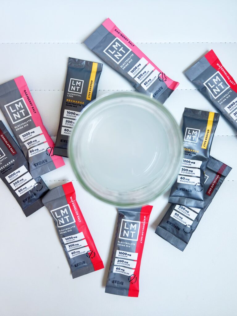 LMNT Electrolyte in glass with variety of flavor packets surrounding