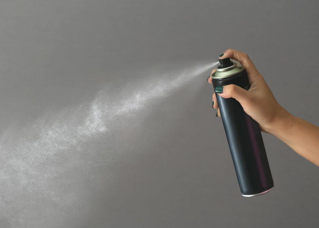 woman spraying aerosol hairspray