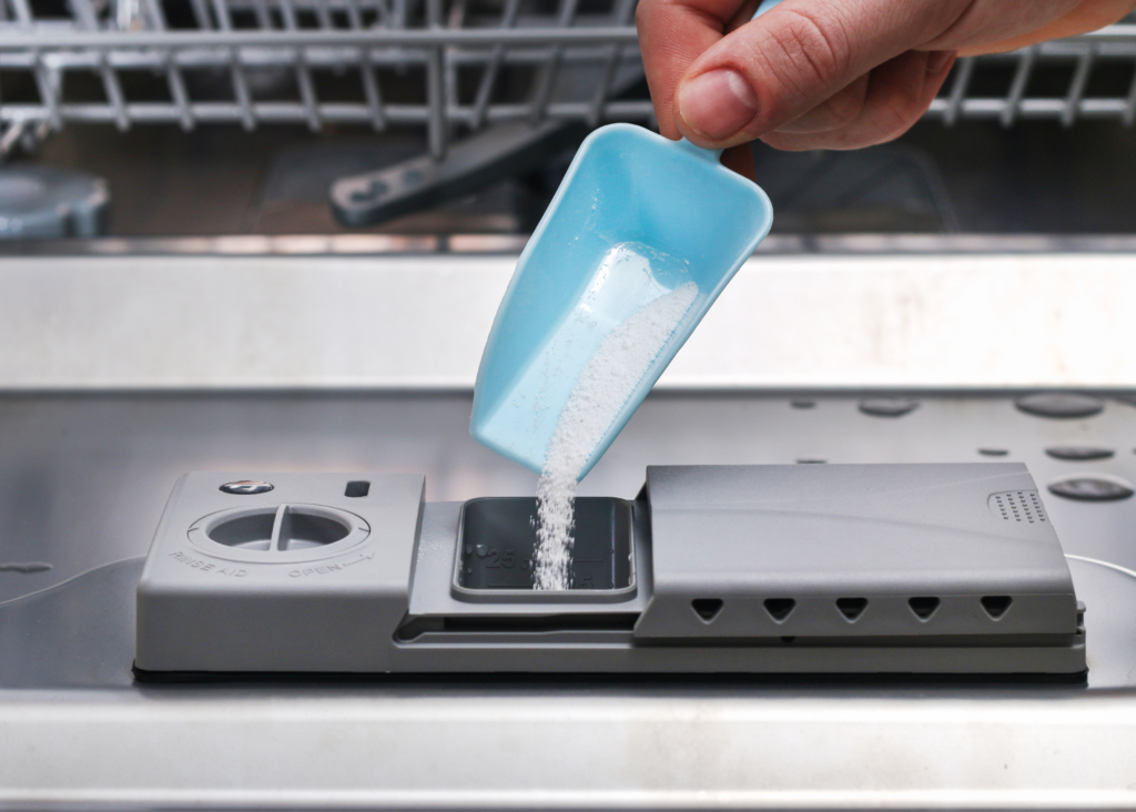 powdered dishwasher detergent being put in a dishwasher