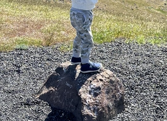 child wearing Vivobarefoot Shoes while climbing on a large rock