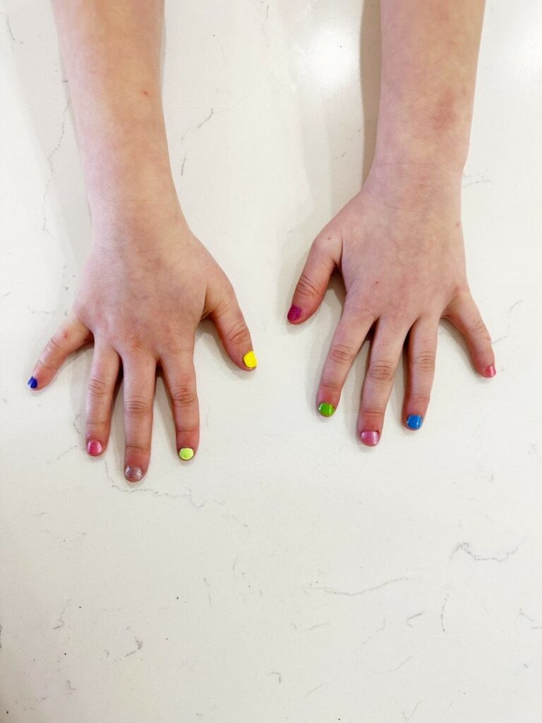 Child's hands wearing multiple non toxic nail polishes
